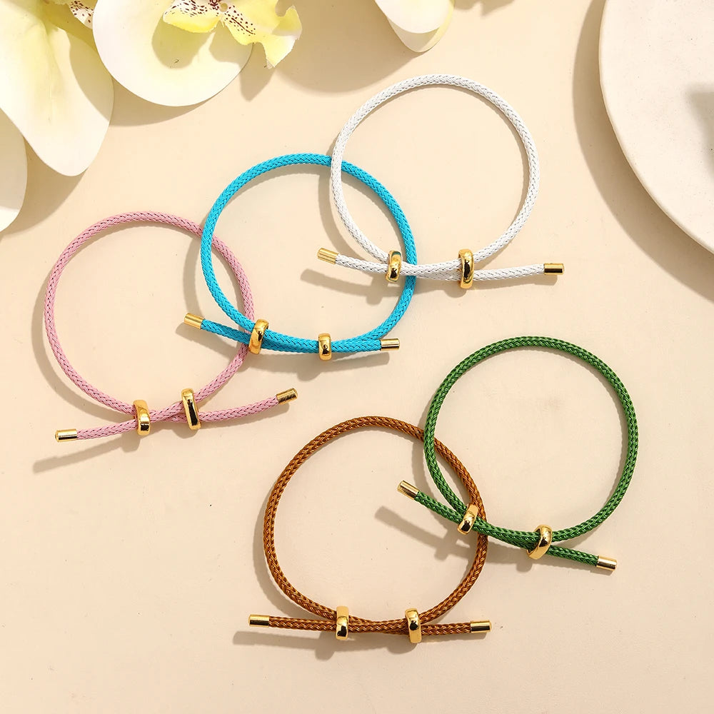 Set of colorful bracelets on a beige surface with flowers in the background