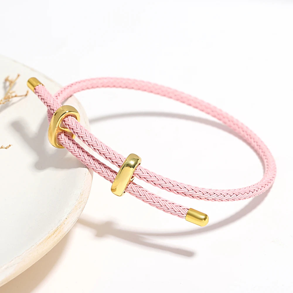 Pink braided bracelet with gold clasps on a white background