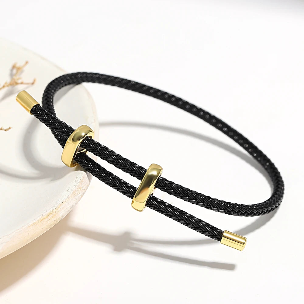Black braided bracelet with gold accents on a white background