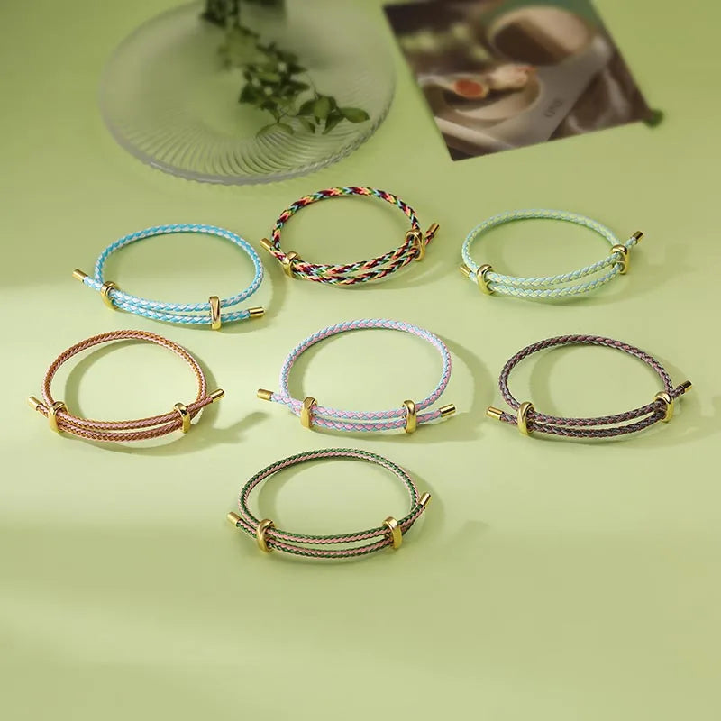 Set of colorful braided bracelets on a light green surface