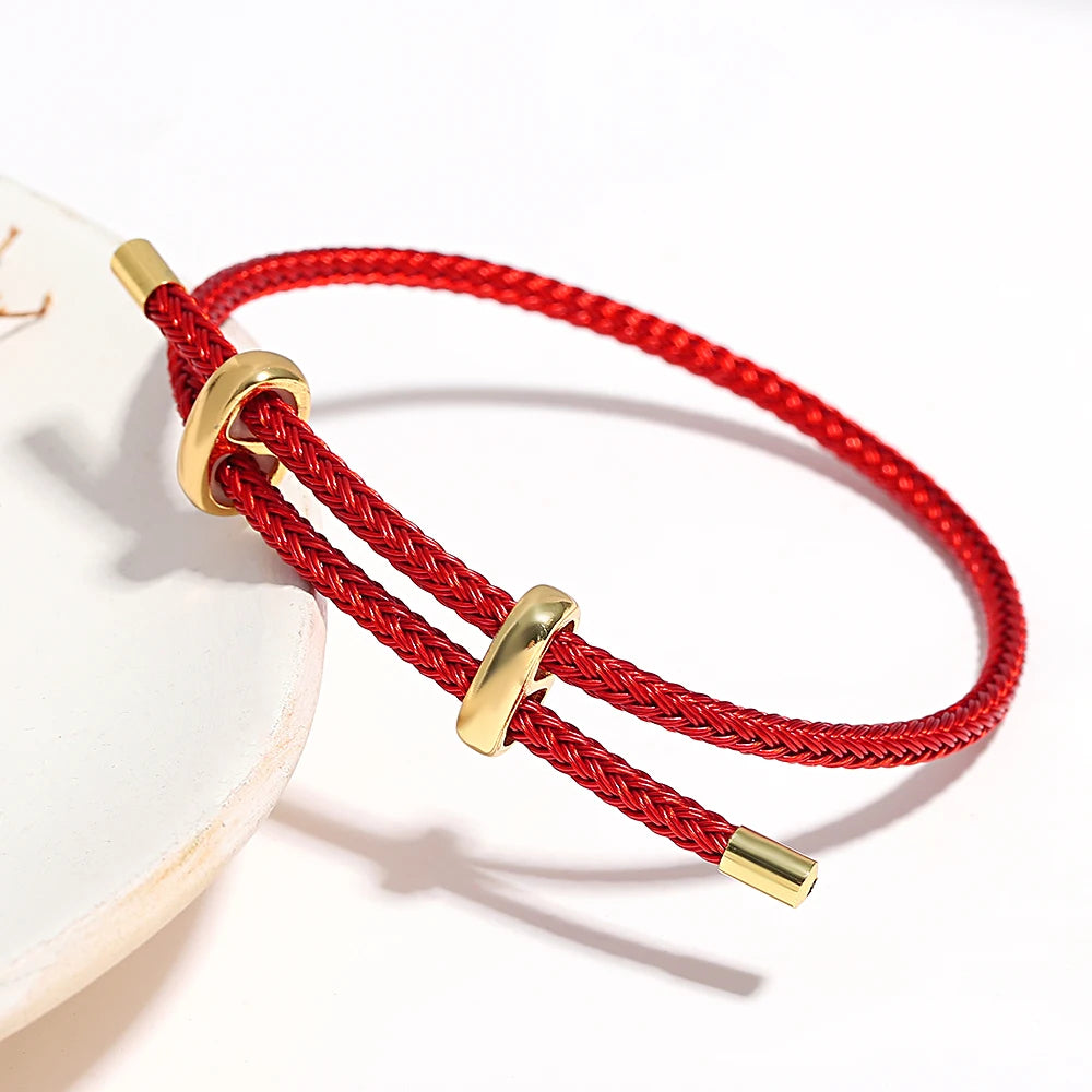 Red braided bracelet with gold accents on a white background